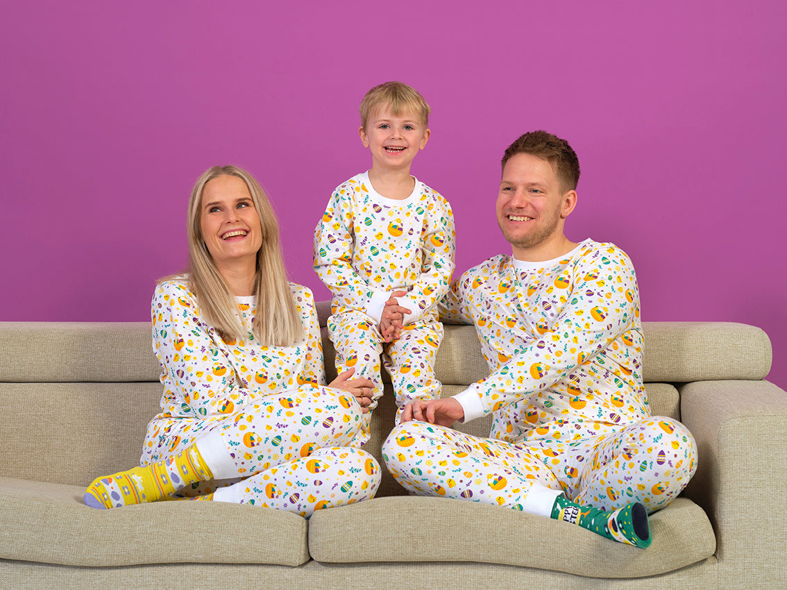 En familie sidder samme i en sofa med påskepyjamas på.